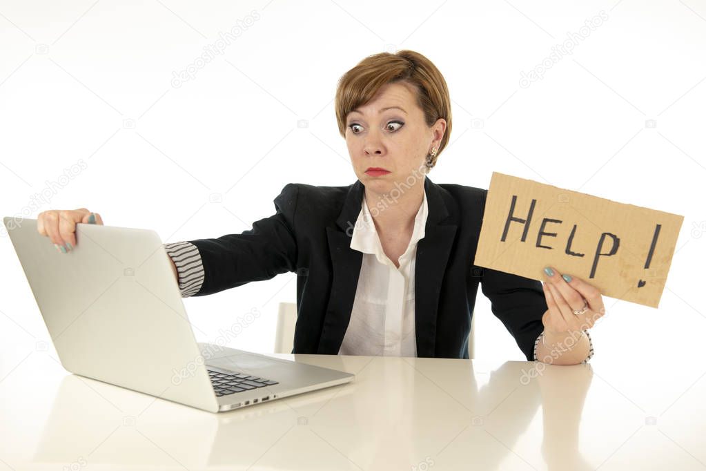 beautiful young red haired caucasian tired and frustrated business woman working on her computer holding a help sign at work office desk on a white background.Stress and business frustration concept