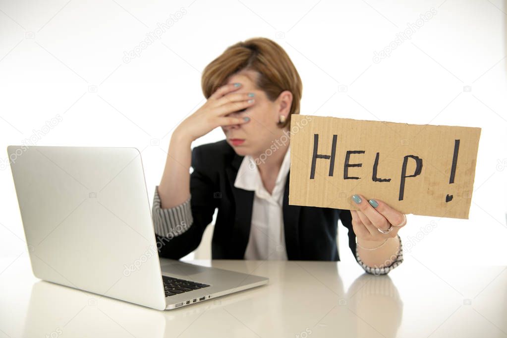 beautiful young red haired caucasian tired and frustrated business woman working on her computer holding a help sign at work office desk on a white background.Stress and business frustration concept.