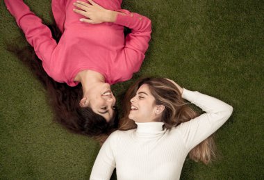İki şık kız arkadaşın gülerken ve çimlerin üzerinde uzanırken yüzlerini allak bullak ettiği bir manzara. Sarışın ve esmer mutlu genç kızlar birlikte vakit geçiriyorlar. Arkadaşlık, sevgi ve ilgi..