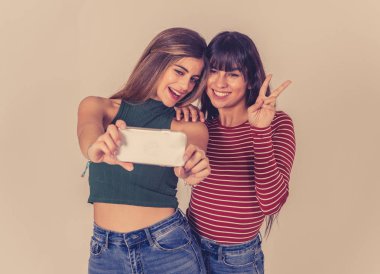 Sosyal medyada selfie çeken ya da blog için video kaydeden iki güzel mutlu kız arkadaş. Birlikte eğlenen iki güzel kadının selfie 'si. İnsanlar, teknoloji, arkadaşlık ve sosyal medya kavramı.