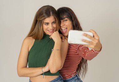 Sosyal medyada selfie çeken ya da blog için video kaydeden iki güzel mutlu kız arkadaş. Birlikte eğlenen iki güzel kadının selfie 'si. İnsanlar, teknoloji, arkadaşlık ve sosyal medya kavramı.