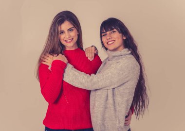 İki şık kız arkadaş gülüyor, sarılıyor ve öpüşüyorlar. Sarışın ve esmer genç kadın modeller birlikte vakit geçiriyorlar ve tarafsız bir arkaplanda poz veriyorlar. Arkadaşlık, sevgi ve ilgi..