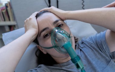 Oksijen maskeli genç çekici bir kadın üzgün ve endişeli görünüyor. Hastane yatağında akciğer kanseri teşhisi, sigara ve solunum hastalıkları ve sigara karşıtı reklam kampanyası..