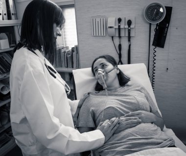 Oksijen maskesi olan genç hasta bir kadın hasta olan kadın doktor acı içinde ve hastanede endişeli görünüyor. Sağlık, sigara ve solunum hastalıklarında ve tütün reklamına karşı kampanyalarda.