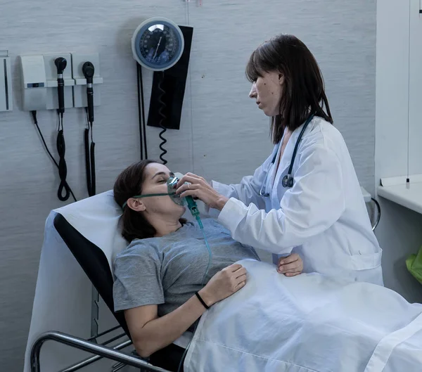 女医生和有氧气面罩的女病人在医院急救室里痛苦而焦虑地看着 在保健 吸烟和呼吸道疾病以及反烟草广告运动方面 — 图库照片