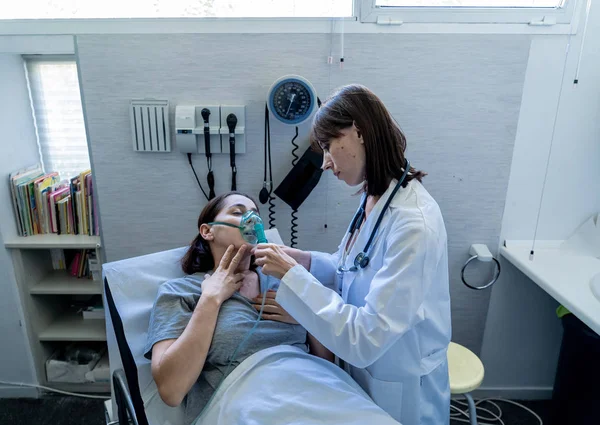 Vrouwelijke Arts Met Jonge Zieke Vrouw Patiënt Met Zuurstofmasker Kijken — Stockfoto