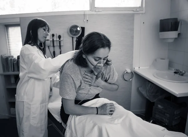 Egy Fiatal Beteg Oxigénmaszkot Visel Míg Női Orvos Sztetoszkóppal Hallgatja — Stock Fotó