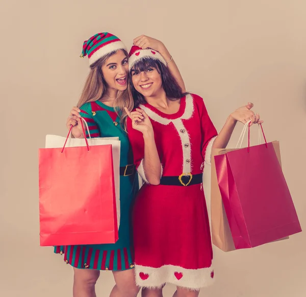 Excited teenagers with shopping bags buying christmas gifts in santa hat and funny christmas outfit. Paper bags with copy space for text. People, holidays, Christmas shopping sales and black friday.