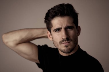 Yakışıklı, yakışıklı bir adamın portresi. Seksi ve şehvetli görünüyor. Güzel siyah evetler ve saçlar. İspanyol erkeksi pozunun stüdyo çekimi. Moda, doğal güzellik, modellik ve yaşam tarzı..