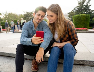 Sosyal medyada genç bir çift akıllı telefon uygulamasını kullanarak blog 'a yorum yapıyor. Çevrimiçi teşvikçilere bakan ve sosyal ağda aile ve arkadaşlarla fotoğraf paylaşan genç adam ve kadın.