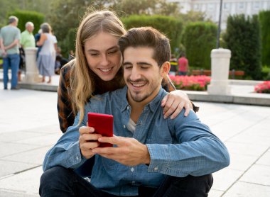 Sosyal medyada genç bir çift akıllı telefon uygulamasını kullanarak blog 'a yorum yapıyor. Çevrimiçi teşvikçilere bakan ve sosyal ağda aile ve arkadaşlarla fotoğraf paylaşan genç adam ve kadın.