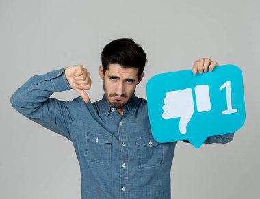Sosyal medyada mutsuz olmanın ve internet takıntısının, sosyal ağ bilgilendirme ikonlarının, siber zorbalığın ve teknoloji iletişiminin reddedilmesinin sosyal medya sembolünü elinde tutan çekici mutsuz genç adam..