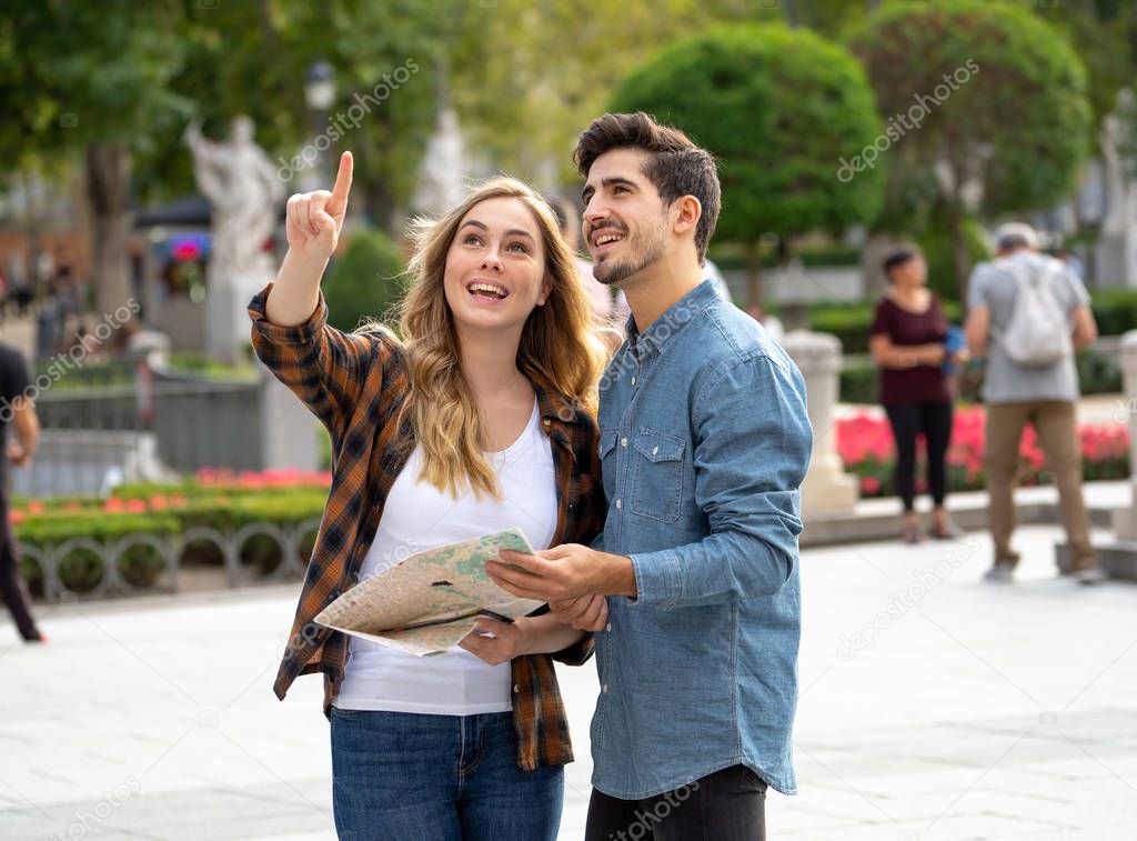 Holidays, dating, city break and tourism concept. Happy young friends tourists couple reading a map and visiting main landmarks while traveling around Europe. Outdoors european city urban background.