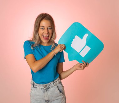 Elinde sembolik sosyal medya bildirim ikonu gibi bir şey tutan güzel genç bir kadın takipçilerden online yorumlarını, blogunu veya işini sevmelerini istiyor. İnternet saplantısı, ağ kurma ve teknoloji bağlantılarında.