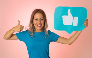 Elinde sembolik sosyal medya bildirim ikonu gibi bir şey tutan güzel genç bir kadın takipçilerden online yorumlarını, blogunu veya işini sevmelerini istiyor. İnternet saplantısı, ağ kurma ve teknoloji bağlantılarında.