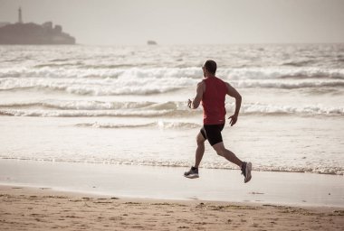 Atlet koşucu adam koşu, sprint ve spor eğitimi gün batımında plajda giymek. Spor ve Aktif sağlıklı yaşam tarzı nda fitness modeli erkek eğitim ve deniz kıyısında açık havada çalışma.