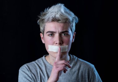 Sansür ve sosyal tabunun kavramsal görüntüsü. Ağzı bantla mühürlenmiş transseksüel genç bir adam. Sessiz bir jest yapıyor. İletişim kuramıyor ya da kendi cinsiyetini ifade edemiyor..