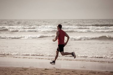 Atlet koşucu adam koşu, sprint ve spor eğitimi gün batımında plajda giymek. Spor ve Aktif sağlıklı yaşam tarzı nda fitness modeli erkek eğitim ve deniz kıyısında açık havada çalışma.