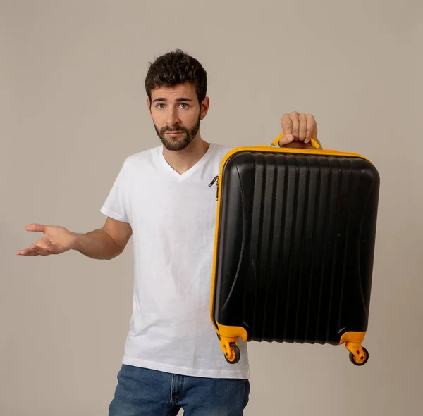 Attractive young traveler man showing suitcase isolated on neutral background. Advertising style image for storage space for travelers, tourism and travel vacation concept.
