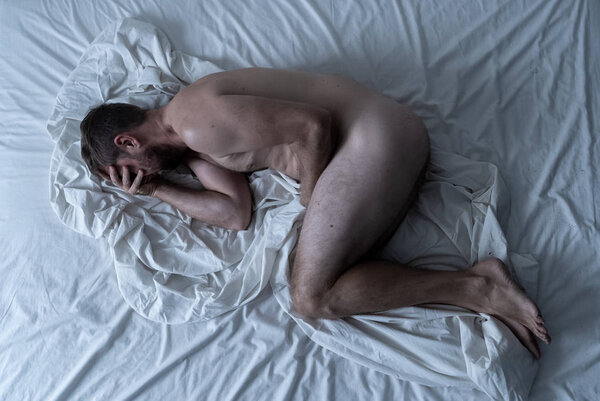 Сексуальное бессилие, вызванное курением сигарет в рекламном имидже против табака. Молодой отчаянный грустный голый мужчина лежит на кровати плачет в одиночестве чувство стыда и опустошенных страданий эректильной дисфункции
.