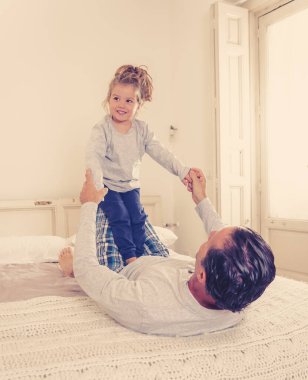 Mutlu bir aile, baba ve tatlı bir kız evde sarılıyor, birlikte gülüyor ve oynuyorlar. Güzel küçük kız babasıyla bağ kurarken, yalnız ebeveyn ve eğitim kavramında eğleniyor..