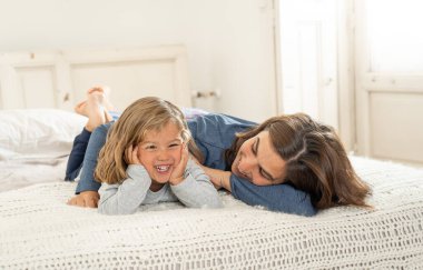 Yatakta dinlenen güzel anne ve kızın hayat tarzı portresi. Anne ve küçük tatlı kız eğleniyor, öpüşüyor ve evde sarılıyorlar. Mutlu aile, eğitim ve tek ebeveyn kavramı.