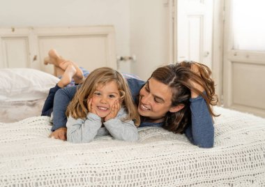 Yatakta dinlenen güzel anne ve kızın hayat tarzı portresi. Anne ve küçük tatlı kız eğleniyor, öpüşüyor ve evde sarılıyorlar. Mutlu aile, eğitim ve tek ebeveyn kavramı.