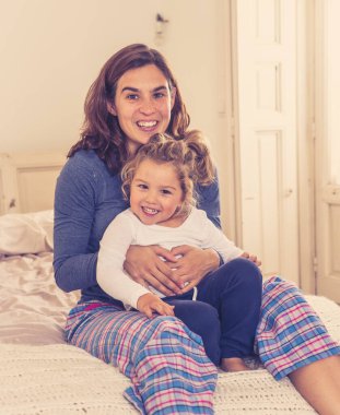 Yatakta dinlenen güzel anne ve kızın hayat tarzı portresi. Anne ve küçük tatlı kız eğleniyor, öpüşüyor ve evde sarılıyorlar. Mutlu aile, eğitim ve tek ebeveyn kavramı.