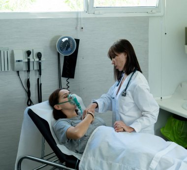 Oksijen maskeli hasta kadın hasta olan kadın doktor acilde acı çekiyor ve endişeli görünüyor. Sağlık hizmetlerinde, sigara ve solunum hastalıklarında ve tütün reklamına karşı kampanyalarda.