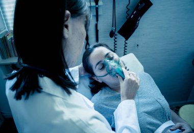 Oksijen maskesi olan genç hasta bir kadın hasta olan kadın doktor acı içinde ve hastanede endişeli görünüyor. Sağlık, sigara ve solunum hastalıklarında ve tütün reklamına karşı kampanyalarda.