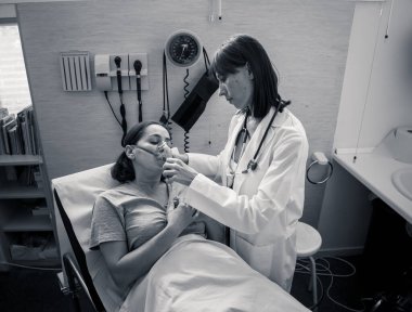 Oksijen maskesi olan genç hasta bir kadın hasta olan kadın doktor acı içinde ve hastanede endişeli görünüyor. Sağlık, sigara ve solunum hastalıklarında ve tütün reklamına karşı kampanyalarda.