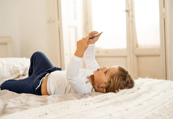 Little caucasian girl on mobile phone playing, watching cartoons or chatting with family. Cute blonde toddler using smart phone In Education and technology, digital generation and phone addiction.