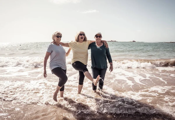 一群可爱的六十多岁的老朋友们散步 在海上洒水 玩得很开心 三个成熟健康的退休女性笑着享受退休生活和户外运动 — 图库照片