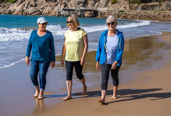由三位60多岁的老年退休妇女组成的一个可爱的小组 他们散步 在度假海滩上玩得很开心 成熟的女性笑着享受友情 度假和退休生活方式概念 — 图库照片