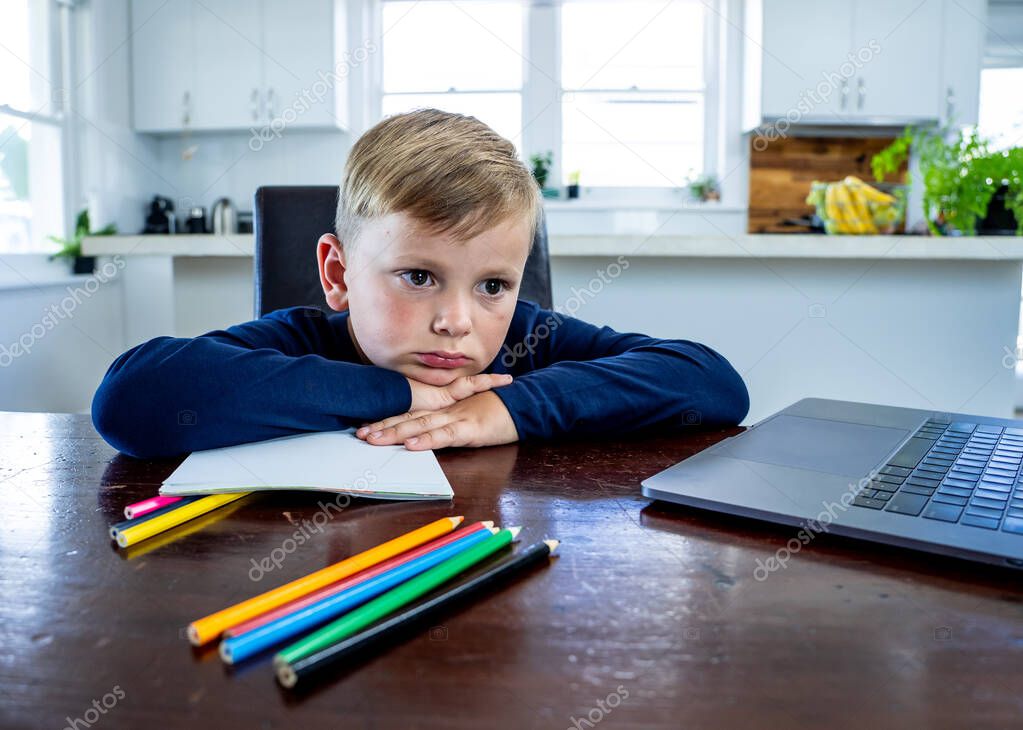 Coronavirus Outbreak. Lockdown and school closures. School boy with face mask watching online education classes feeling bored and depressed at home. COVID-19 pandemic forces children online learning.