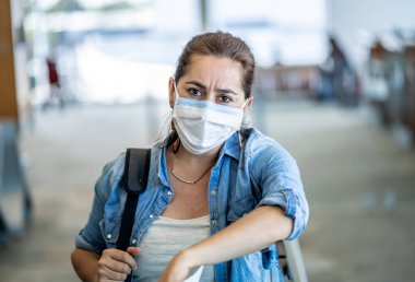 Coronavirus salgını seyahat kısıtlamaları. Uluslararası havaalanında maskeli gezginler uçuşların iptalinden ve seyahat yasağından etkilendiler. COVID-19 salgını dünya çapında sınır kapatma ve kapatma.