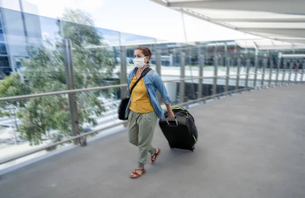 Coronavirus outbreak travel ban and restrictions. Traveler man with face mask at international airport affected by flight cancellation. COVID-19 pandemic and worldwide borders closures and shutdowns.