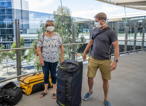 Coronavirus outbreak travel ban and restrictions. Traveler man with face mask at international airport affected by flight cancellation. COVID-19 pandemic and worldwide borders closures and shutdowns.