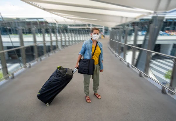 Coronavirus outbreak travel ban and restrictions. Traveler man with face mask at international airport affected by flight cancellation. COVID-19 pandemic and worldwide borders closures and shutdowns.