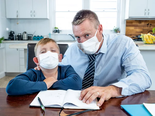 Coronavirus Outbreak school shutdowns. Stressed parent coping with remote work and homeschooling worried about COVID-19 pandemic. Father and son with mask in quarantine working and learning from home.
