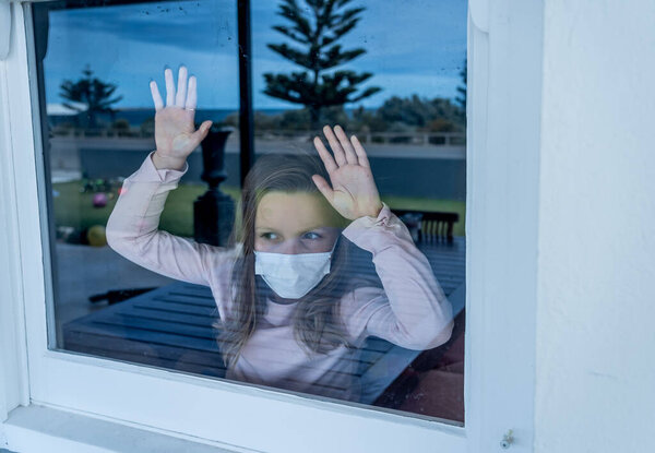 COVID-19 Lockdown. Депрессивная одинокая девочка в маске, смотрящая в окно во время карантина. Грустный больной ребенок в изоляции дома. Вспышка коронавирусу и психическое здоровье детей
.