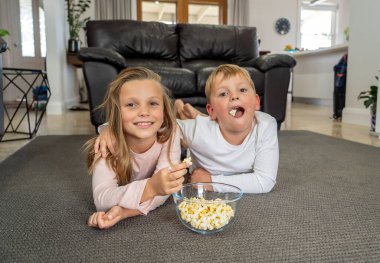 COVID-19 salgını, tecrit. Evde kal, hayat kurtar. Kafkasyalı çocukla kız tecritte mutlu bir şekilde karantina sırasında televizyon izleyerek eğleniyorlar. Koronavirüsün yayılmasını engellemek için..