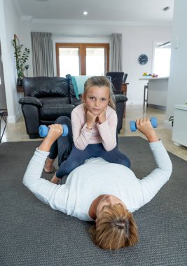 COVID-19 kapatma. Anne, Lockdon sırasında fiziksel olarak aktif kalmaya çalışan sıkılmış küçük kızıyla egzersiz yapıyor. Evde kal, sağlık, egzersiz ve koronavirüs izolasyonu için kendine dikkat et..