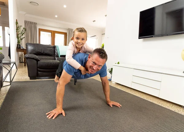 COVID-19 shutdown. Happy father and daughter exercising together during quarantine. Family having fun doing indoors physical activity. Stay home, Exercise, Health Self-care for Coronavirus isolation.