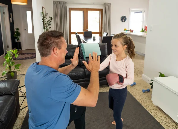 COVID-19 shutdown. Happy father and daughter boxing together during quarantine. Family having fun doing indoors physical activity. Stay home, Exercise, Health Self-care for Coronavirus isolation.