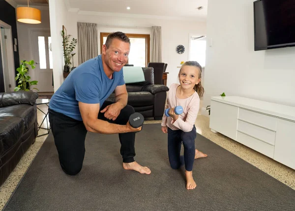 COVID-19 shutdown. Father and daughter in quarantine exercising together with dumbbells. Benefits of physical activity during lockdown. Stay at home, Health and Self-care for Coronavirus isolation.