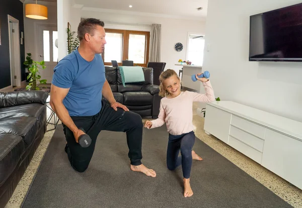 COVID-19 shutdown. Father and daughter in quarantine exercising together with dumbbells. Benefits of physical activity during lockdown. Stay at home, Health and Self-care for Coronavirus isolation.