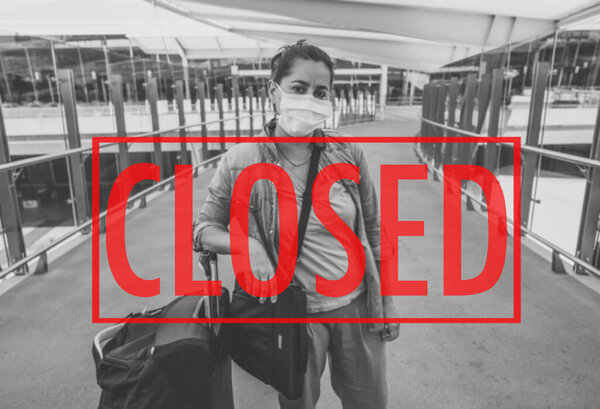 COVID-19 Запрет на вспышки и перемещения. Женщина-путешественница в маске для лица в аэропорту, пострадавшем от отмены рейса из-за пандемии коронавируса и закрытия границ по всему миру словом Закрыто красным
.