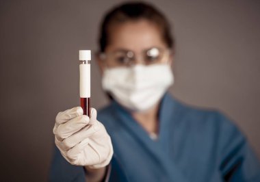 COVID-19. PPE 'deki doktor ya da laboratuvar teknisyeni. Kişisel koruyucu ekipman. Hastanedeki hastadan alınan kan örneği tüpünü tutuyor. Antikor ve aşı araştırmaları için Coronavirus kan testi.