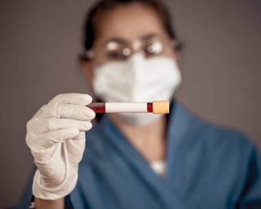 COVID-19. PPE 'deki doktor ya da laboratuvar teknisyeni. Kişisel koruyucu ekipman. Hastanedeki hastadan alınan kan örneği tüpünü tutuyor. Antikor ve aşı araştırmaları için Coronavirus kan testi.